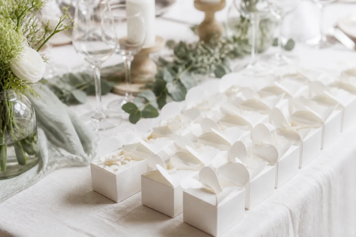 Boîtes à dragées blanches alignées sur une table, prêtes à être garnies et fermées